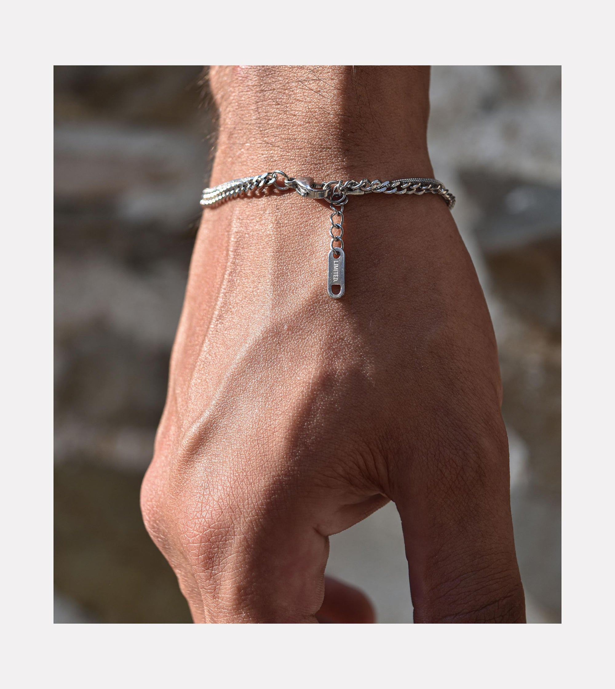 Close-up view of LIMITED. stainless steel double chain bracelet on model's wrist with engraved tag